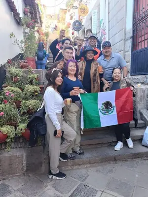a group of people standing on steps holding a flag at 7 Borreguitos GUESTHOUSE in Cusco