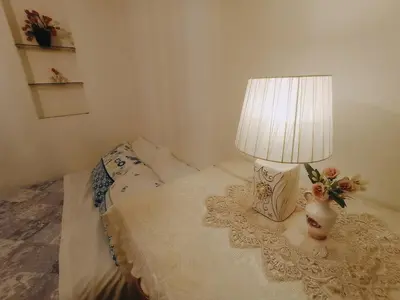 a bed with a lamp and a vase with flowers on it at Cómodo e independiente minidepartamento a pasos del Circuito Mágico in Lima