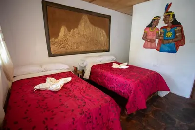 two beds with red covers in a room with a painting at Viamonte EcoLodge in Santa Teresa