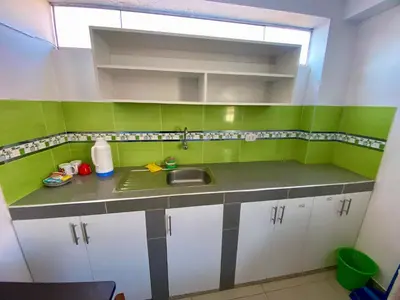a kitchen with green and white cabinets and a sink at Marlen's Qorywasi in Cusco