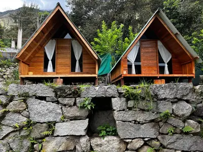a cabin in a stone wall next to a house at ALPHINA CABINS Qhapaq Ñan in Sahuayacu