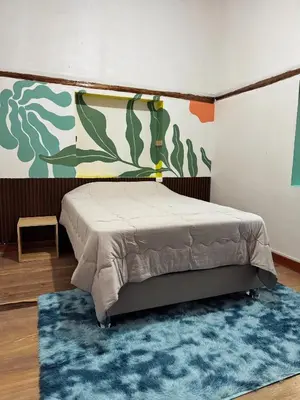 a bedroom with a bed and a blue rug at Casa Muyuna in Calca