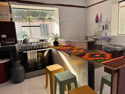 a kitchen with a stove and a counter with stools at Casa Muyuna in Calca