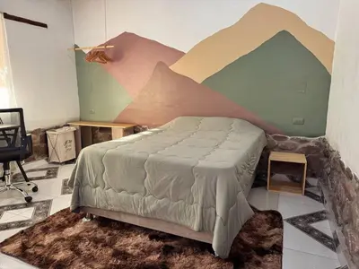 a bedroom with a bed with a painting on the wall at Casa Muyuna in Calca