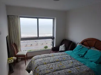 a bedroom with a bed and a view of the ocean at Departamento Costa Verde San M in Lima