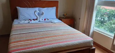 a bedroom with a bed with swans pillows and a window at Haylli Café Oro Hotel in Santa Teresa