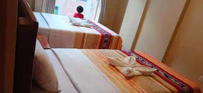 two beds in a room with flowers on them at Haylli Café Oro Hotel in Santa Teresa