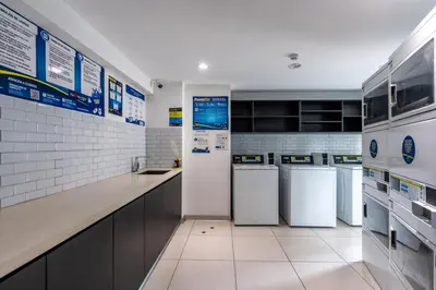 a large kitchen with white appliances and white tiles at Sunline 2BR by Geko in Lima
