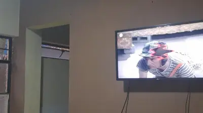 a television hanging on a wall with a baseball player on it at Your home in the city awaits in Lima