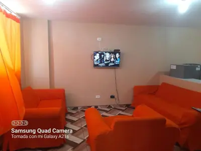 a waiting room with orange chairs and a tv at Your home in the city awaits in Lima