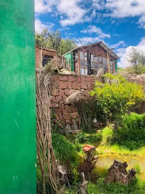 a painting of a building behind a stone wall at Sumaqay Lodge -Naturaleza Arte y Arquitectura