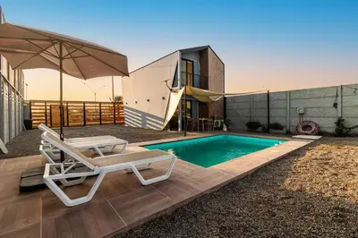 a swimming pool with a chair and an umbrella at Tiny House con Piscina Privada, AC and Starlink in Paracas