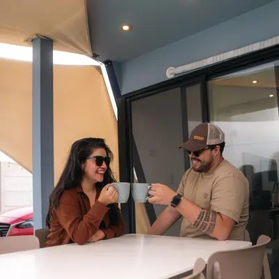 a man and woman sitting at a table drinking coffee at Tiny House con Piscina Privada, AC and Starlink in Paracas