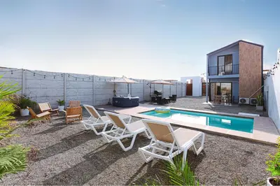 a backyard with a pool and chairs and a house at Tiny House con Piscina Privada, Jacuzzi, Parrilla y Starlink in Punta Negra