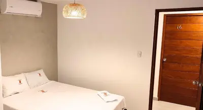 a small room with a bed and a wooden door at Hostal Pulpos in Bombiso