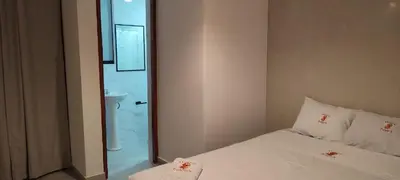 a bedroom with a white bed and a shower at Hostal Pulpos in Bombiso