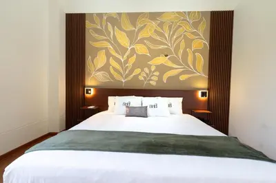 a bedroom with a large white bed with a painting on the wall at Bosco Hotel Boutique in Cusco