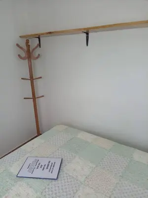 a sign on a bed with a cross on the wall at Mi lagartitas Bungalow in Oxapampa