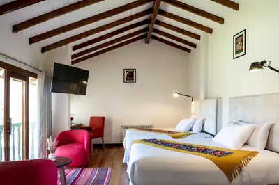 a hotel room with two beds and a tv at Casa Eva Hotel Boutique in Urubamba