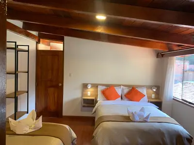 a bedroom with two beds with orange pillows at Juliet's House in Ollantaytambo