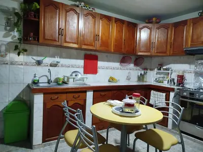 a kitchen with wooden cabinets and a yellow table and chairs at Habitación H4, TV y WIFI cerca a Barranco in Lima