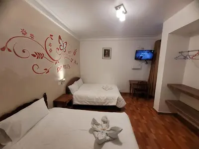 a room with two beds and a tv in it at HOTEL HUAYNAPATA Pardo in Cusco