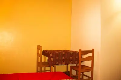 a room with two chairs and a table and a wall at Hospedaje Pumayalli in Urubamba