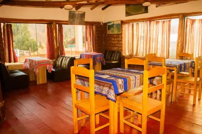 a dining room with a table and chairs and windows at Hospedaje Pumayalli in Urubamba