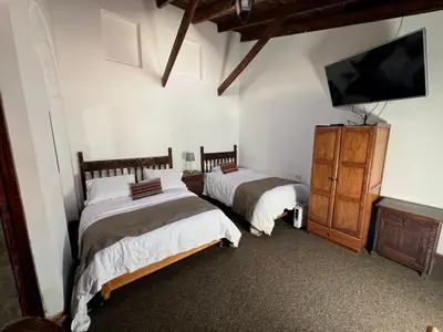 a bedroom with two beds and a flat screen tv at Inka Tambo Hacienda in Cusco