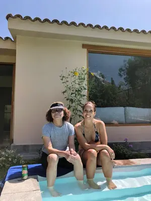 two women sitting next to a swimming pool at Tornameza Casa de Campo in Torna Mesa