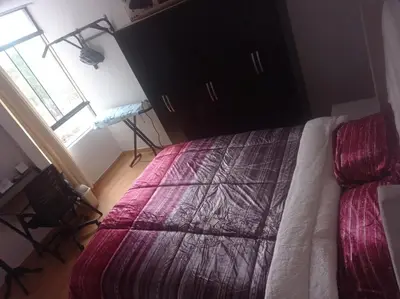 a bedroom with a bed with a purple comforter and a window at Apartment 12 min from airport in Lima