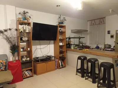 a living room with a flat screen tv and stools at Apartment 12 min from airport in Lima