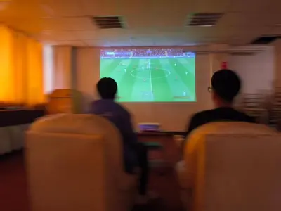 two people watching a soccer game on a screen at Waalay Hotel in Huancayo