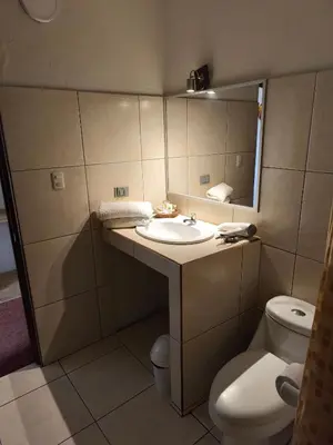 a bathroom with a sink and a toilet and a mirror at Waalay Hotel in Huancayo