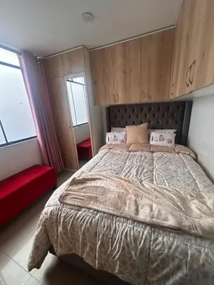 a bedroom with a large bed and a red couch at Departamento Palmeras in Lima