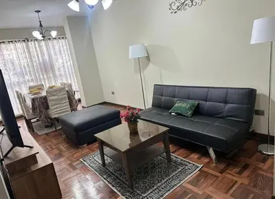 a living room with a black couch and a table at Departamento centrico cusco in Cusco