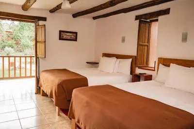 a hotel room with two beds and a balcony at Lizzy Wasi Urubamba in Urubamba