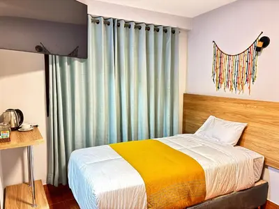 a bedroom with a bed with a yellow and white blanket at Hotel Litan Machu Picchu in Machu Picchu