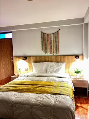 a bedroom with a large bed with a yellow blanket at Hotel Litan Machu Picchu in Machu Picchu