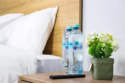 two bottles of water on a table next to a bed at Hotel Litan Machu Picchu in Machu Picchu