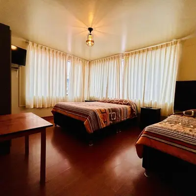 a hotel room with two beds and a table at Hotel la Casa de Makito's in Cusco