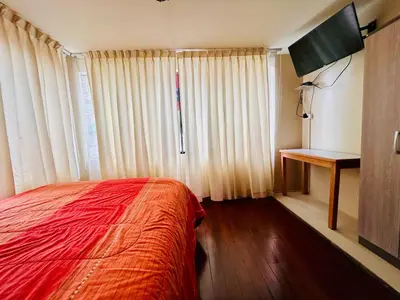 a bedroom with a red bed and a television in it at Hotel la Casa de Makito's in Cusco