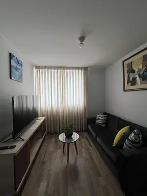 a living room with a black couch and a table at Apartamento en Santa Beatriz in Lima