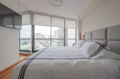 a bedroom with a large white bed with a large window at Luxury apartment in Miraflores near Larcomar in Lima