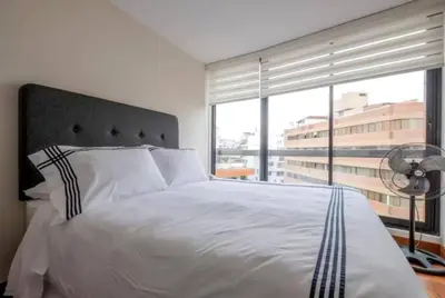 a bedroom with a white bed with a large window at Luxury apartment in Miraflores near Larcomar in Lima