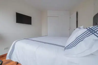 a bedroom with a white bed with a television on it at Luxury apartment in Miraflores near Larcomar in Lima