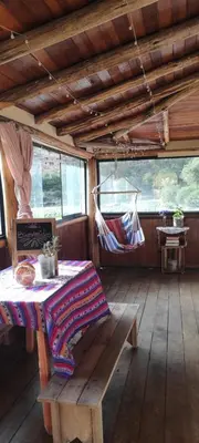a room with a table and a hammock in a cabin at Cabaña rodeada de naturaleza en Ollantaytambo in Ollantaytambo