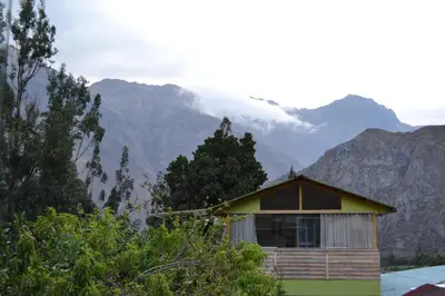 a small house with mountains in the background at Cabaña rodeada de naturaleza en Ollantaytambo in Ollantaytambo
