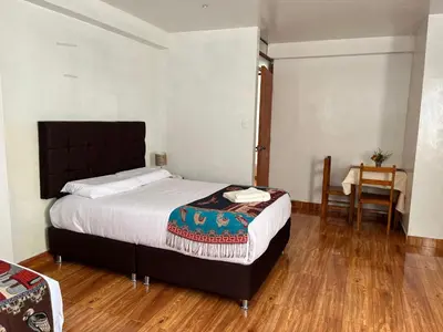 a bedroom with a bed and a table and a chair at Tikary Lodge in Cusco