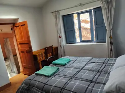 a bedroom with a bed with green sheets and a window at Minidepartamento amoblado in Cusco